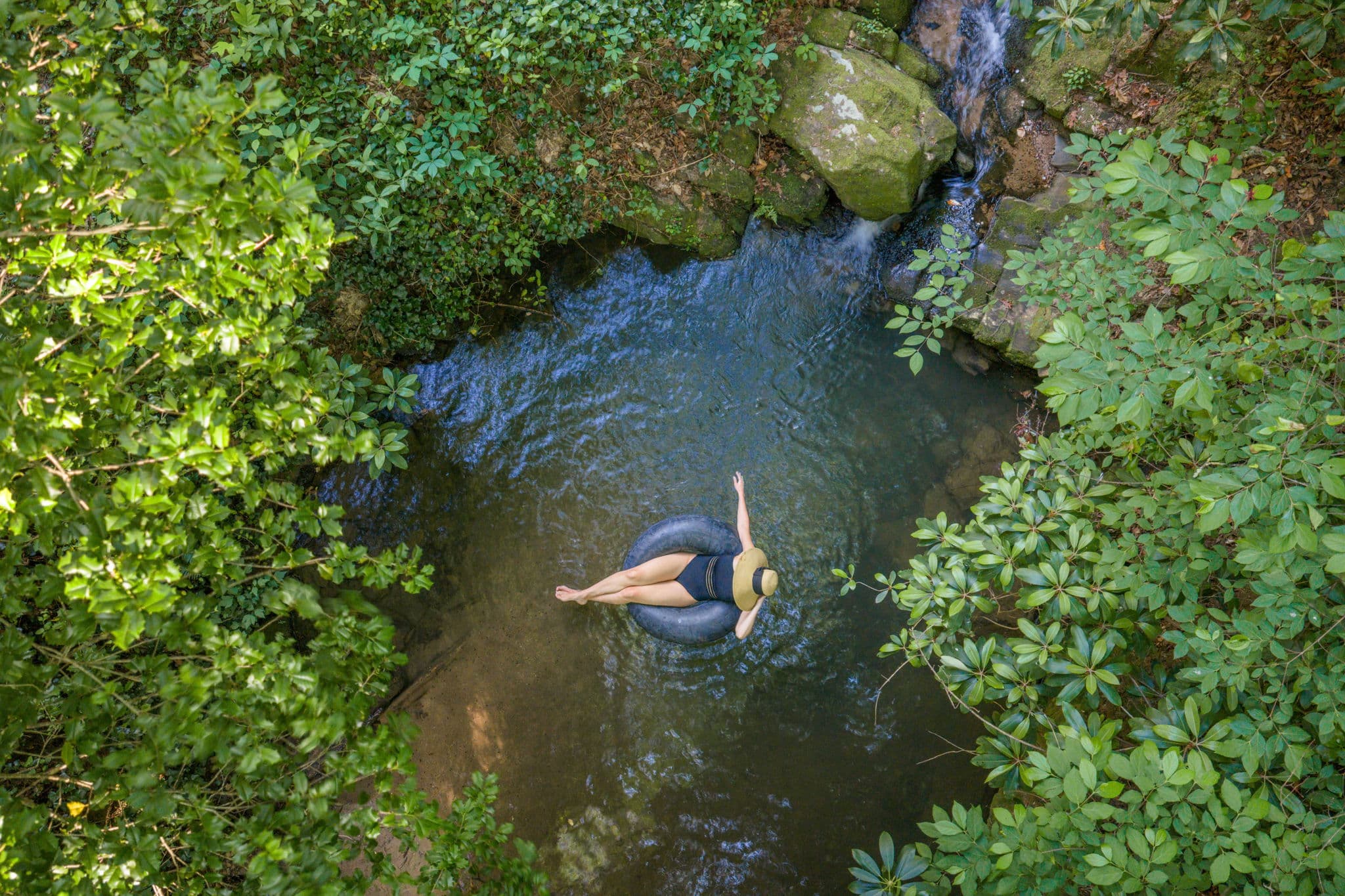 Aerial view of person floating in inner tube in the private swimming hole at Falling Water vacation rental Dahlonega Georgia