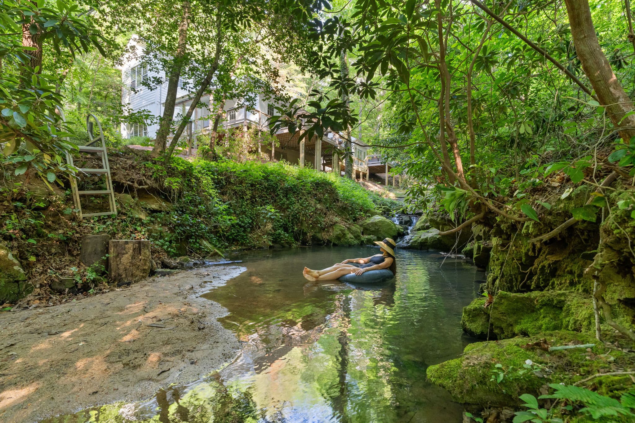 Person floating in the natural creek and swimming hole at Falling Water vacation rental Dahlonega Georgia